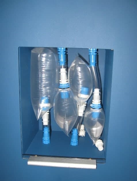 Four clear plastic bags of gas hanging side by side inside a blue cabinet, each with a blue valve.